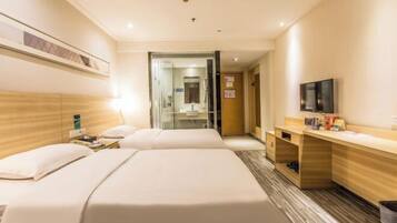 A hotel room with two beds, a desk, a television, and a shower area.