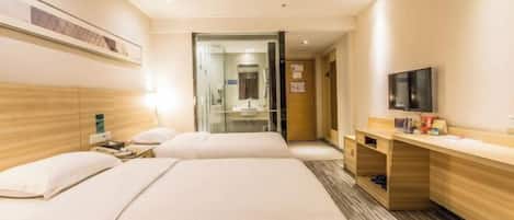 A hotel room with two beds, a desk, a television, and a shower area.