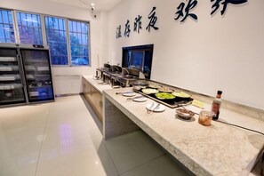A buffet area with a marble counter, various food dishes, a refrigerator, and a wall with Chinese characters. - Mingdu Hotel (Ningming)
