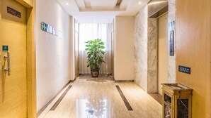 A hotel hallway with a marble floor, a potted plant, and an elevator. - Mingdu Hotel (Ningming)