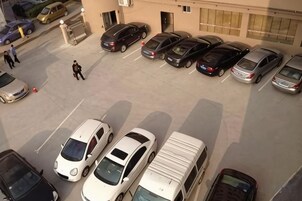 Un estacionamiento con varios automóviles y un edificio al fondo.