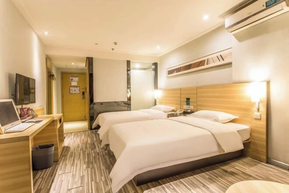 Une chambre d’hôtel avec deux lits, un bureau avec un ordinateur portable, une télévision et un appareil de climatisation.