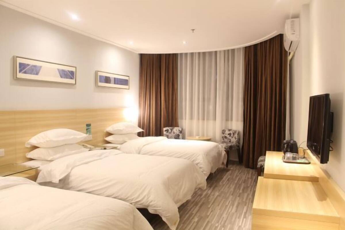 Une chambre d’hôtel avec deux lits, un bureau, une chaise, une télévision et un appareil de climatisation.