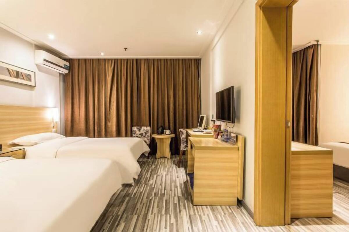 Une chambre d’hôtel avec deux lits, un bureau, une télévision et une armoire.