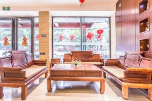 Un vestíbulo con mobiliario de madera, ventanas amplias y detalles en rojo.