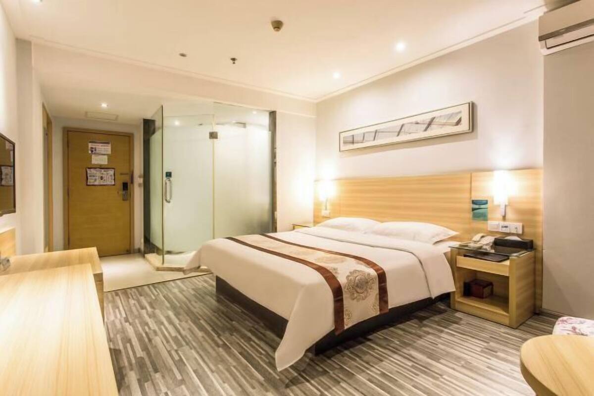 Une chambre d’hôtel avec un lit, une table de chevet, une lampe et une vue sur le couloir.