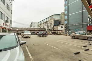 Vista de la calle con coches estacionados, edificios y un puente peatonal.