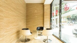 A modern interior with a marble wall, a glass window with a view of the street, and three white chairs with black cushions. - Mingdu Hotel (Ningming)