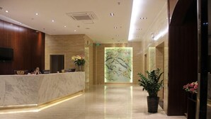 A hotel lobby with a marble reception desk, a large wall mural, and potted plants. - Mingdu Hotel (Ningming)