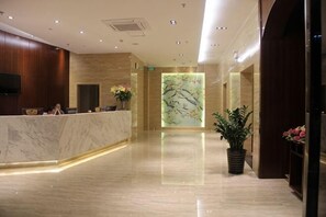 A hotel lobby with a marble reception desk, a large wall mural, and potted plants. - Mingdu Hotel (Ningming)