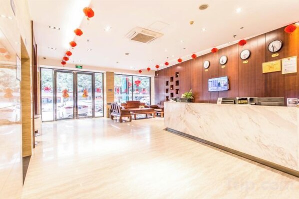 A hotel reception area with a marble counter, wooden paneling, clocks, and a television. - Mingdu Hotel (Ningming)