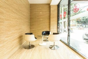 A modern interior with a seating area by a window, a wooden floor, and a wall with a textured pattern.
