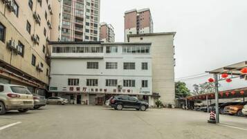 A multi-story building with a ground-level entrance, parked cars, and a visible sign.
