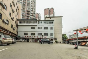 A multi-story building with a ground-level entrance, parked cars, and a visible sign.