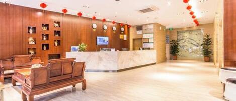 A hotel lobby with a reception desk, seating area, and decorative elements.