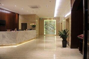 A hotel lobby with a reception desk, a large abstract wall art, and potted plants. - Mingdu Hotel (Ningming)