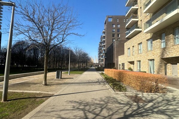 A modern apartment building with a central courtyard, a pathway, and a row of trees. - Cosy Thameside Retreat in North Greenwich (London)