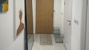 A hallway with a wooden door, a metal rack, and a rug on the floor. - Cosy Thameside Retreat in North Greenwich (London)