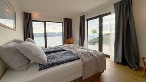 A bedroom with a large bed, a view of the sea, and a balcony. - Villa Ena in peaceful location with a sea view (Zagorje)