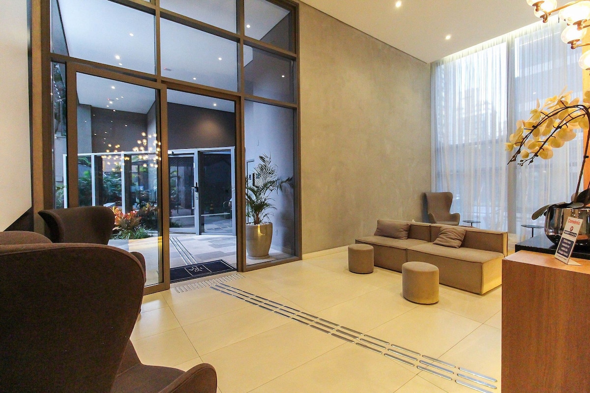 A modern lobby with a sofa, chairs, a reception desk, and large windows.