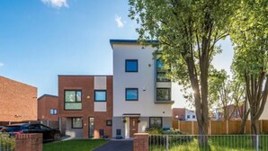 A modern two-story apartment building with a flat roof, large windows, and a visible entrance. - Manchester Oasis Retreat - 4 Bedroom House (Manchester)