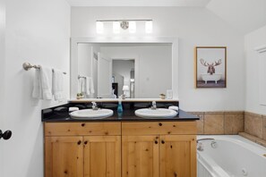 A bathroom with a double sink vanity, a large mirror, and a framed picture on the wall.