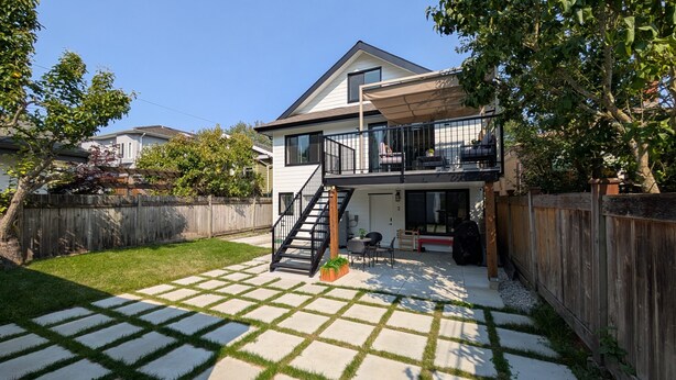 A two-story house with a visible staircase leading to the upper floor, a fenced backyard, and a patio area with outdoor furniture. - Bright 2-Bed Ground Suite | Steps to PNE & Transit (Vancouver)