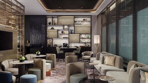 Eine moderne Lounge mit Sofas, Sesseln und einem Couchtisch, mit Marmorwand und einem gemusterten Teppich.