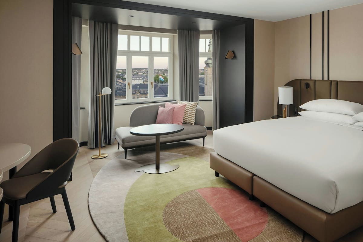 Une chambre d’hôtel avec un lit, un canapé, une table ronde et une chaise.
