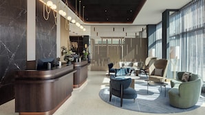Eine moderne Lobby mit Empfangstresen, Sitzgelegenheiten und großen Fenstern.