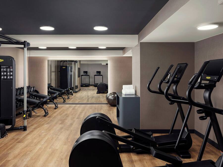 Una sala de gimnàstica moderna amb equipament cardiovascular, aparells de peses i un mirall gran.