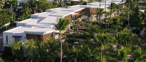 A modern resort with multiple buildings, palm trees, and a pool area.