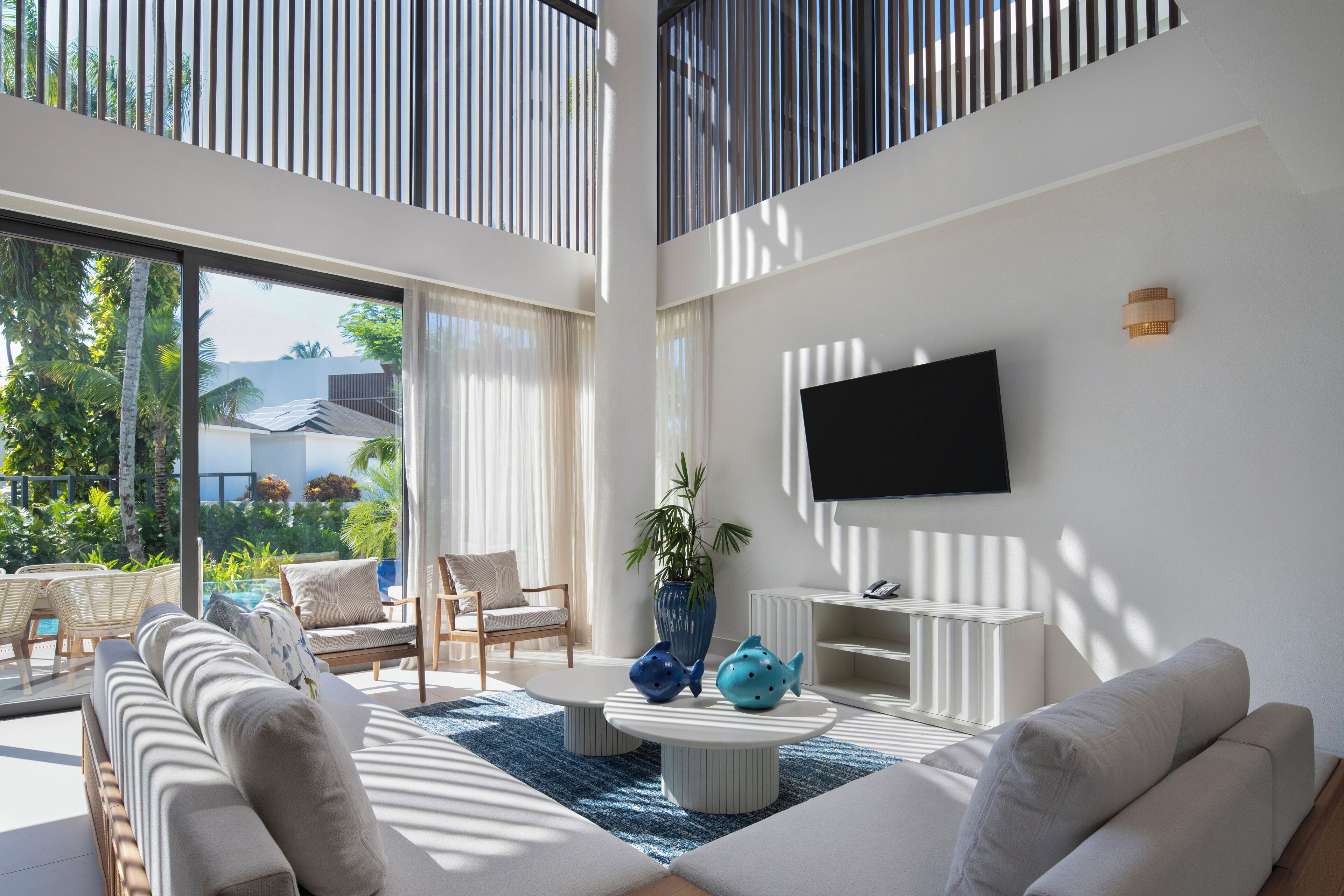 Una sala de estar moderna con un televisor grande, asientos cómodos, una mesa de centro y vistas al exterior.