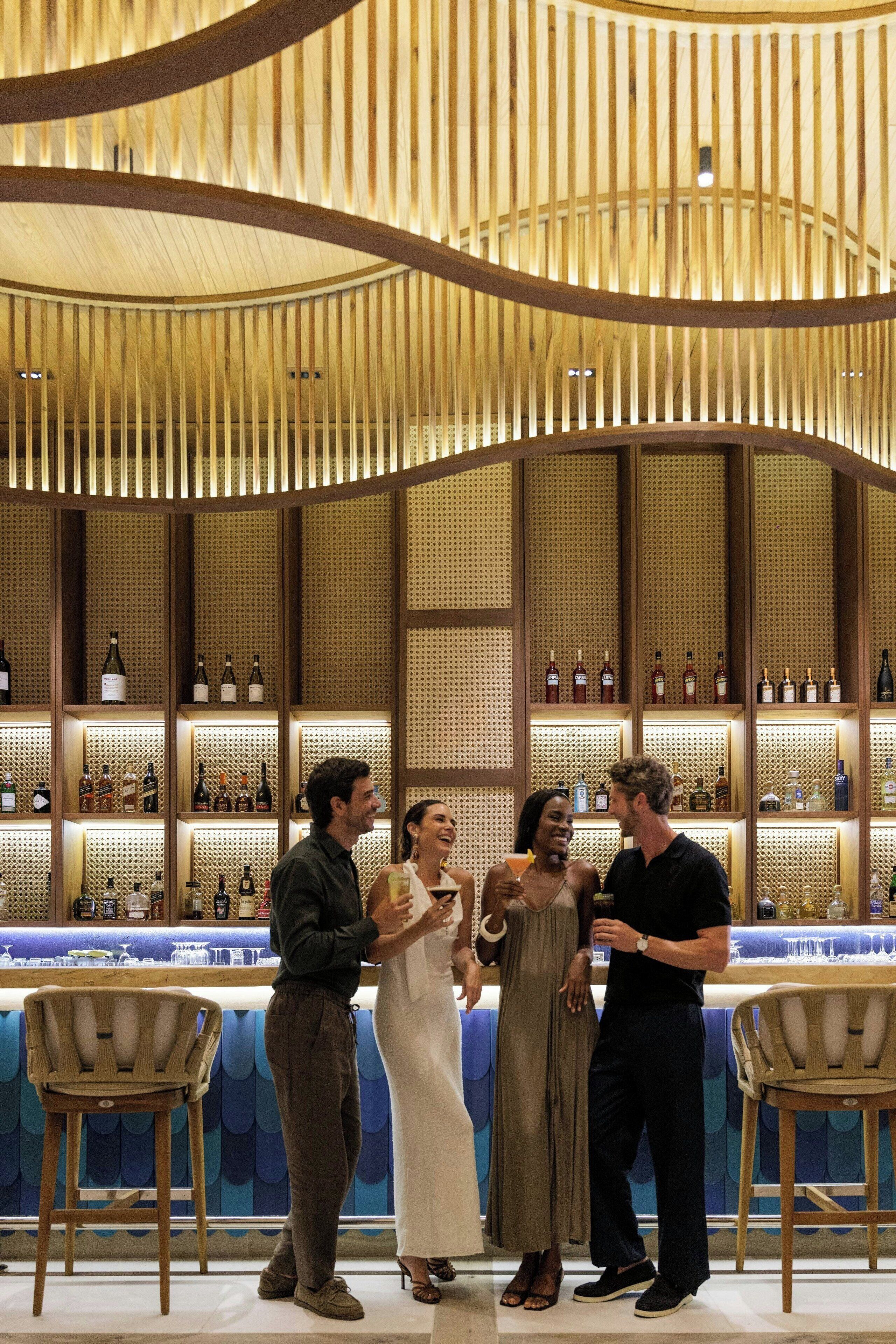 Un bar con listones de madera en el techo, una barra y estantes con botellas.
