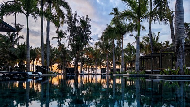 A pool with palm trees and a sunset in the background. - Donoma Las Terrenas Resort & Villas Autograph Collection (Las Terrenas)