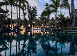 A pool with palm trees and a sunset in the background. - Donoma Las Terrenas Resort & Villas Autograph Collection (Las Terrenas)