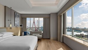 A modern hotel room with a large bed, a seating area with a view of a cityscape and a bridge, and large windows. - Shanghai Marriott Hotel Yangpu Riverside (Shanghai)