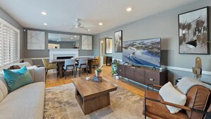A modern living room with a sofa, coffee table, TV, and dining area.