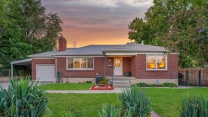 A two-story brick house with a garage, a front porch, and a well-maintained lawn.