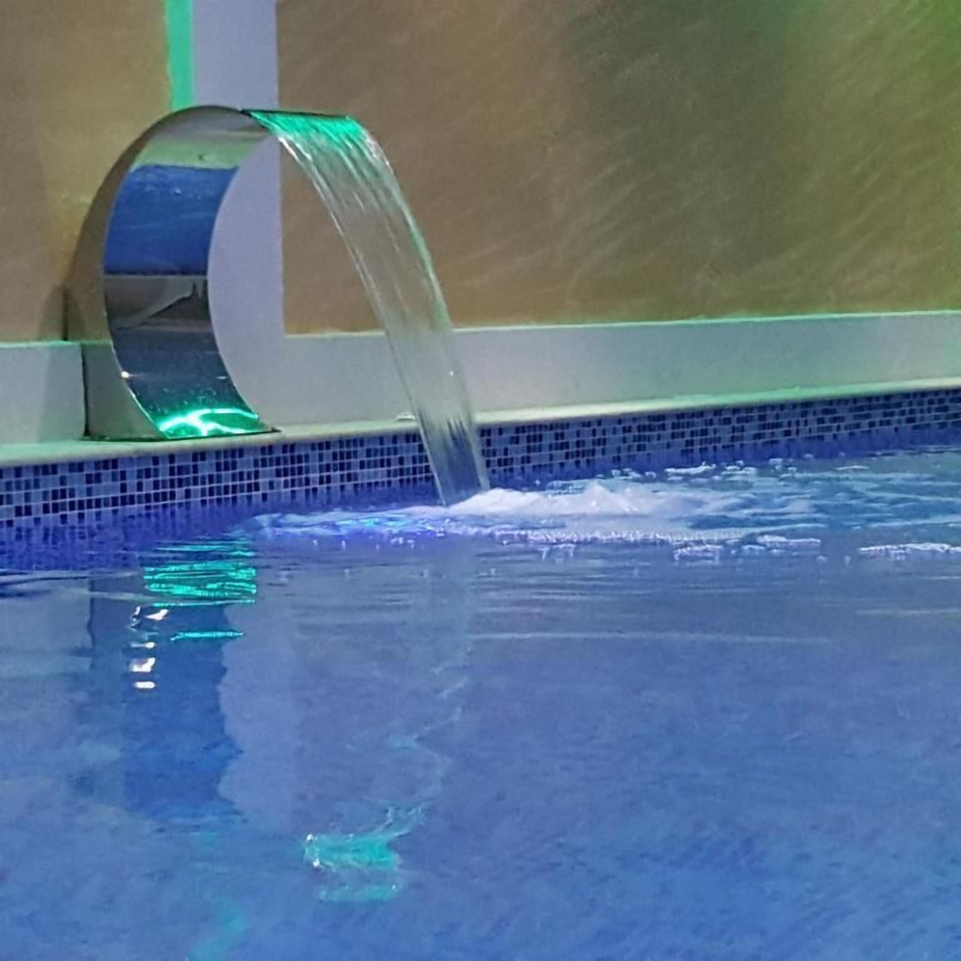 A pool with a clear water feature and a tiled edge.