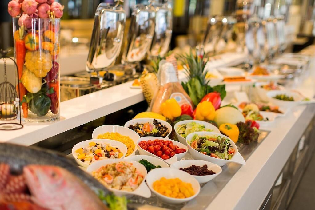 A buffet with various dishes including salads, fruits, and seafood.