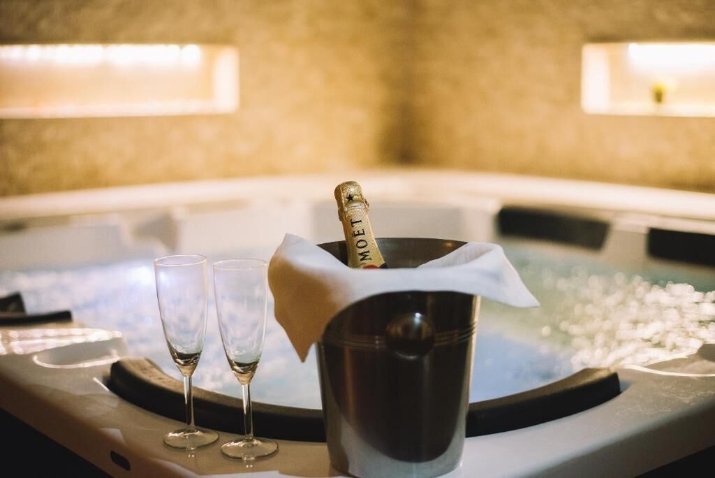 A hot tub with a champagne bottle and two glasses.