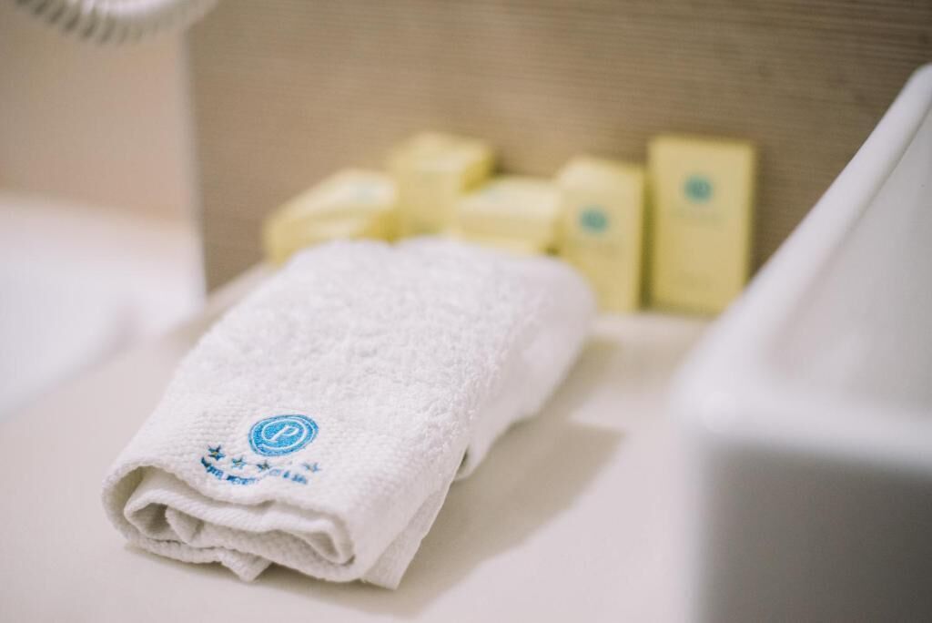 A neatly folded white towel with a logo on a wooden surface, accompanied by several yellow bars, likely soap or lotion.