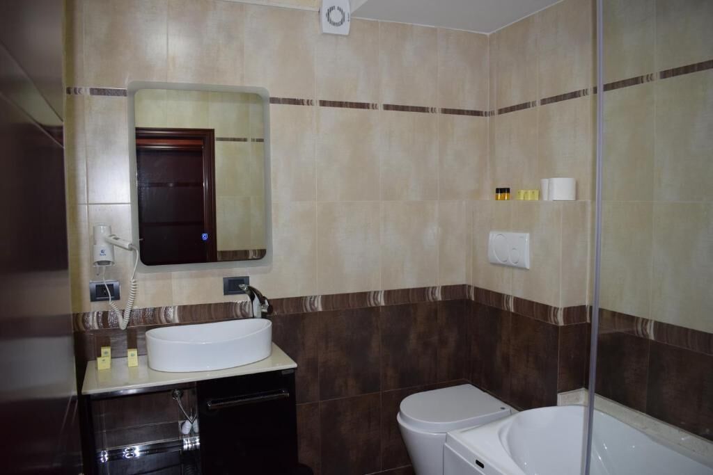 Un baño con lavamanos, espejo, inodoro y bañera.