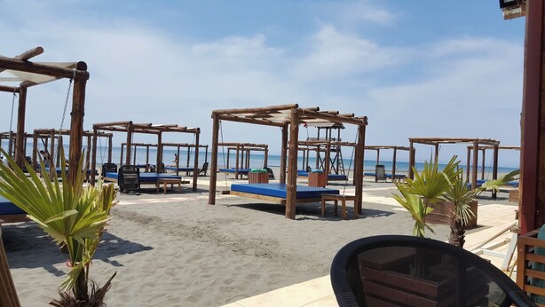 A beachside seating area with wooden structures and blue cushions. - Petriti & spa (Ulcinj)