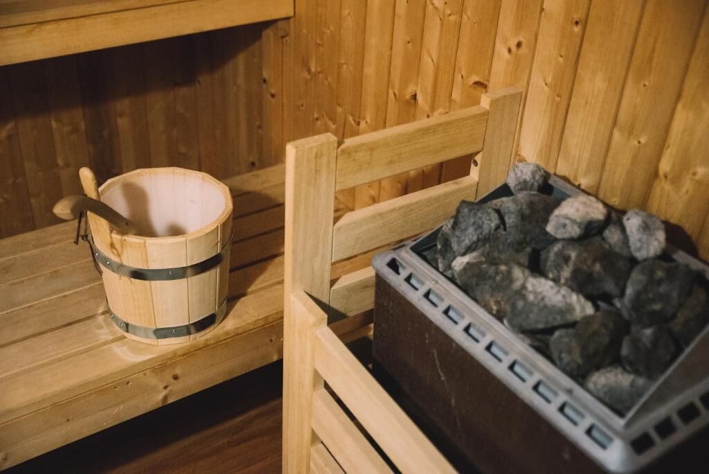 A wooden sauna with a wooden bucket and a container of stones.