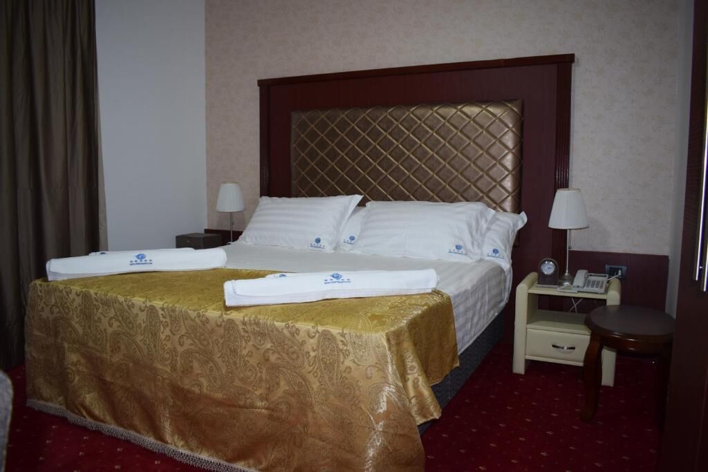 Una habitación de hotel con una cama grande, dos mesitas de noche y una pequeña mesita auxiliar.