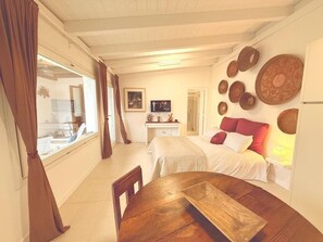 A cozy bedroom with a bed, a bedside table, and a window with curtains. - Pisu Apartments (Bonarina apartment)  (Quartucciu)