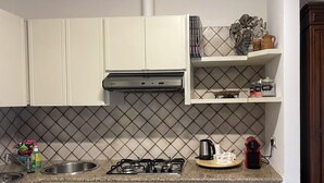 A kitchen with white cabinets, a gas stove, a sink, and a coffee machine. - Pisu Apartments (Bonarina apartment)  (Quartucciu)