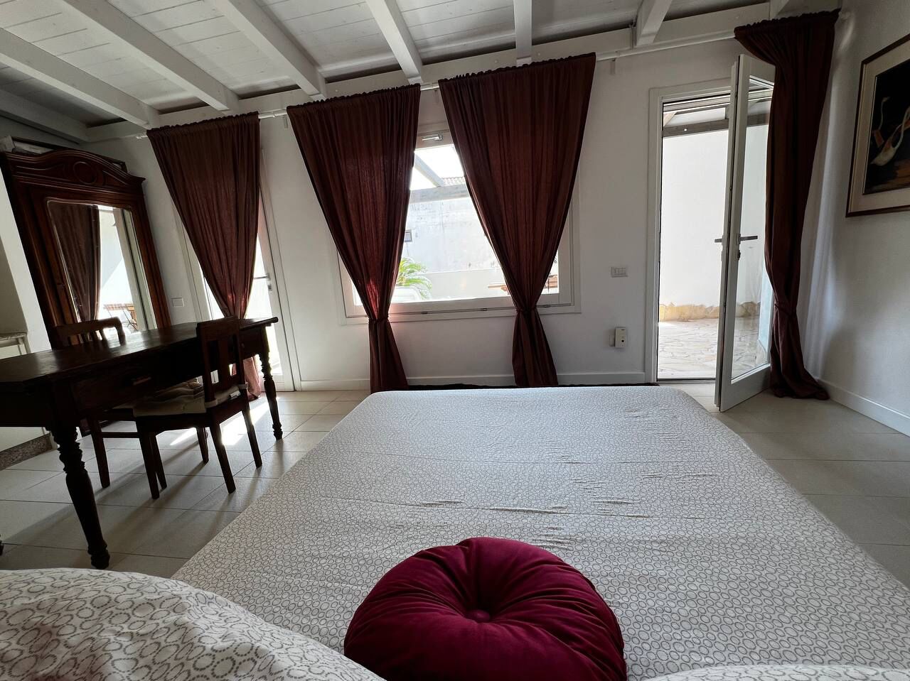Una camera da letto con un letto grande, un tavolo da pranzo in legno con sedie e una finestra con tende.